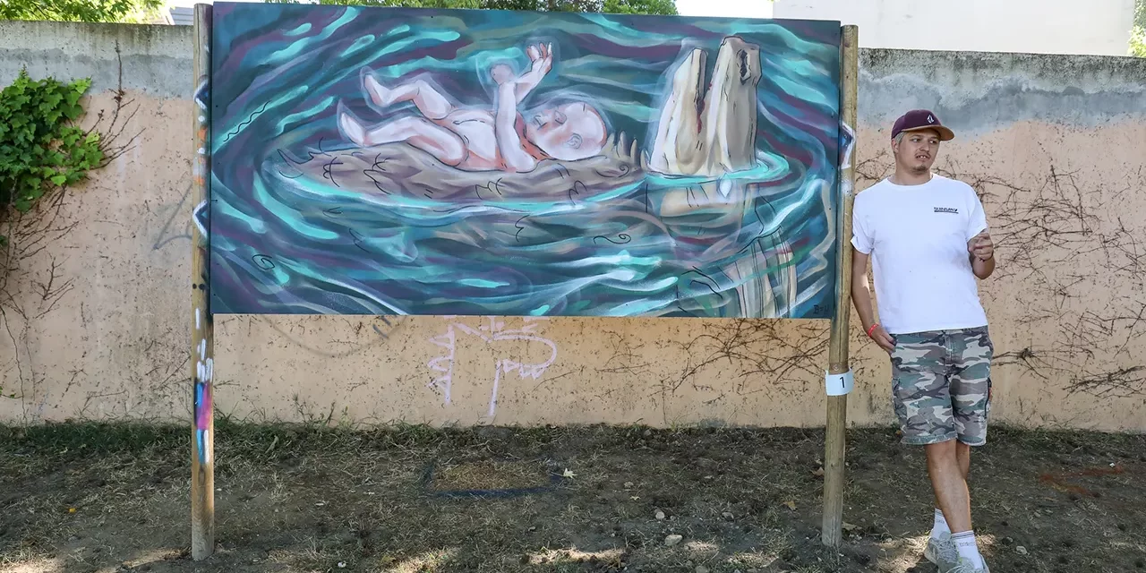 Artiste espagnol, Oriol B=K pose devant son œuvre réalisée pendant le concours de street-art.